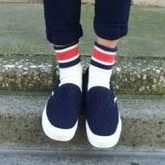 グレーのニットとデニムを着て黒のスリッポンを履いた女性