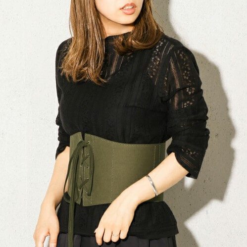 黒レーストップスにカーキのコルセットベルトをした女性