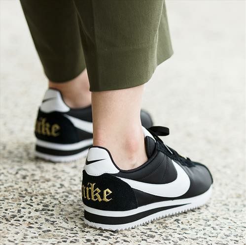 カーキパンツに黒いナイキのスニーカーを履いた女性の足