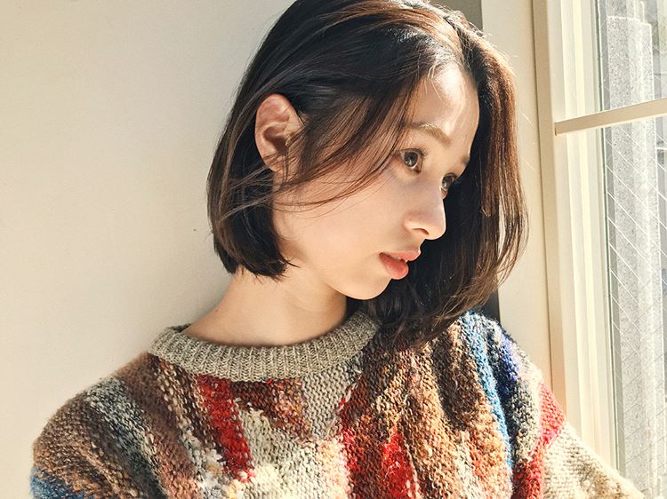 長い前髪をかきあげているボブヘアスタイルの女性