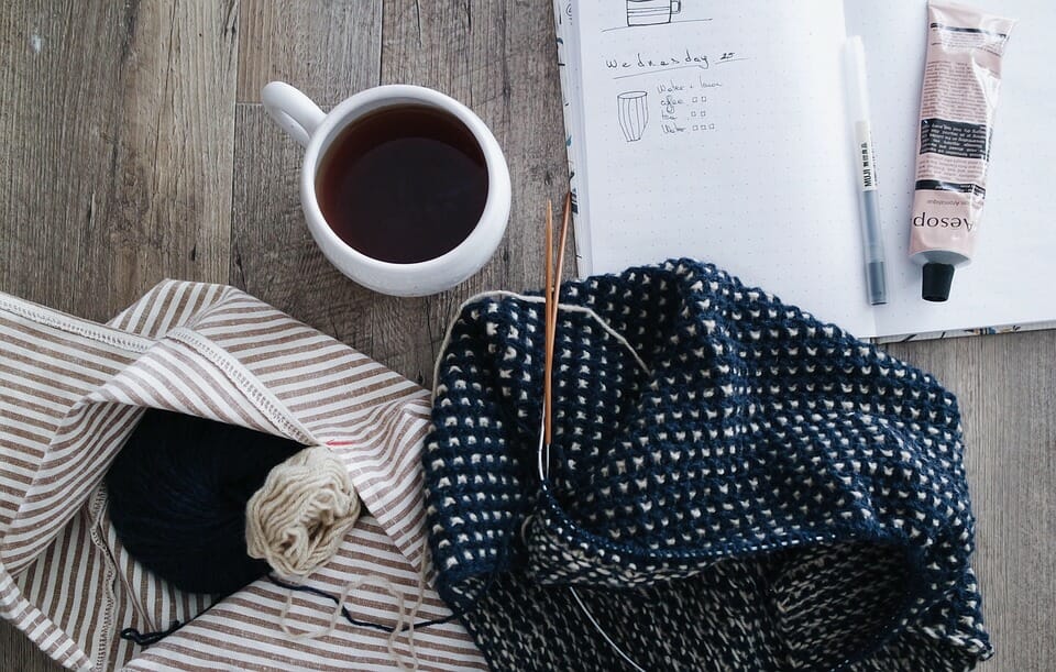 コーヒーを飲みながら毛糸で編んだ編み物と文房具を置いたデスク