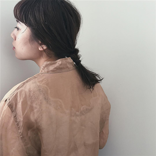 伸ばしかけのミディアムヘアを低めポニーテールにヘアアレンジした女性