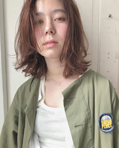 前髪をセンター分けにセットした伸ばしかけボブヘアの髪型の女性