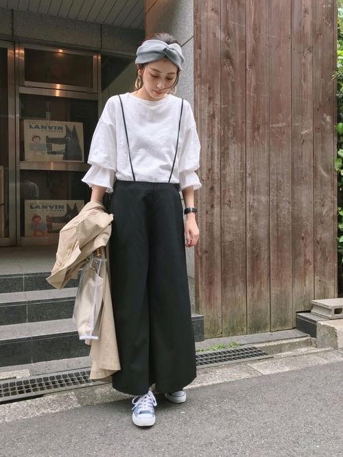 白のトップスに黒のサロペットを着た女性