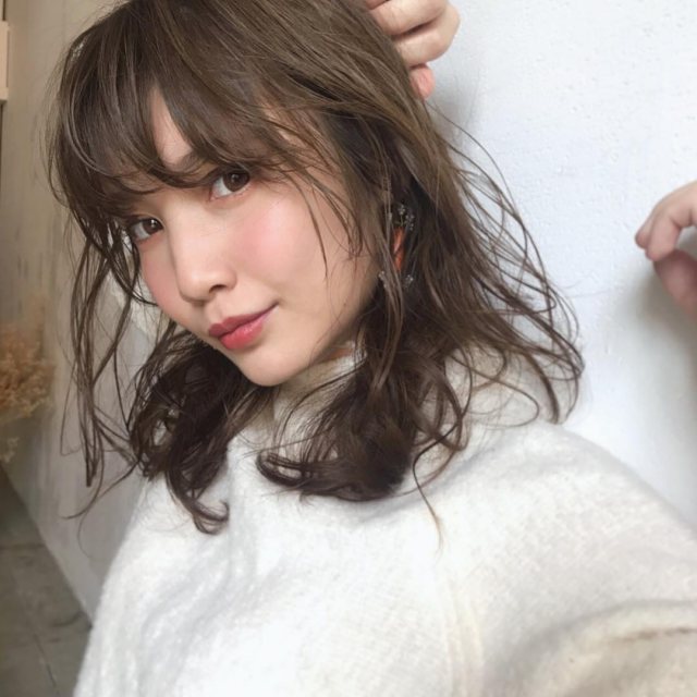 丸顔さんに似合う髪型の前髪ありの無造作パーマミディアムヘアスタイルにした女性の画像