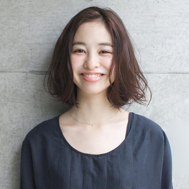 丸顔さんに似合う髪型の前髪なしのゆるふわパーマミディアムヘアスタイルにした女性の画像