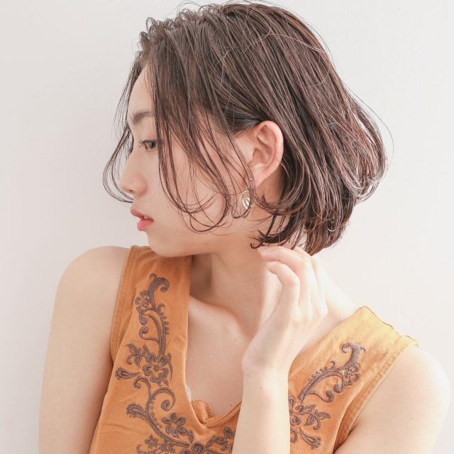 丸顔さんに似合う髪型の前髪なしのウェットパーマボブヘアスタイルにした女性の画像
