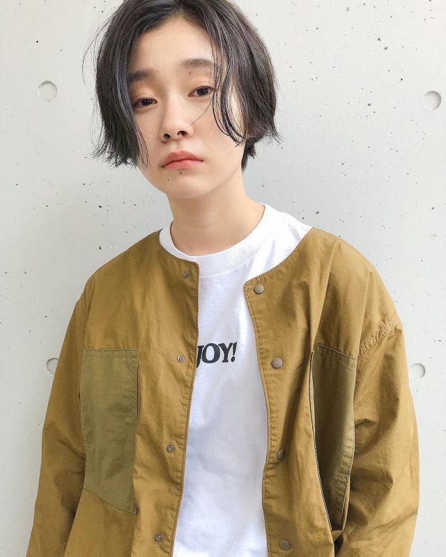 丸顔さんに似合う髪型の前髪なしの黒髪ショートヘアスタイルにした女性がロゴTシャツを着た画像