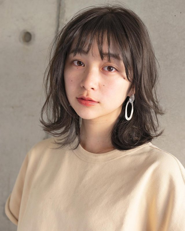 丸顔さんに似合う髪型の前髪ありのナチュラルパーマミディアムヘアスタイルにした女性の画像