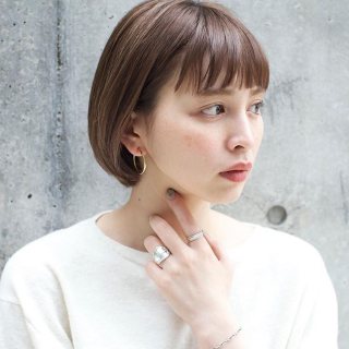 前髪ありのミニボブヘアスタイルの髪型を耳にかけてスタイリングアレンジしている女性