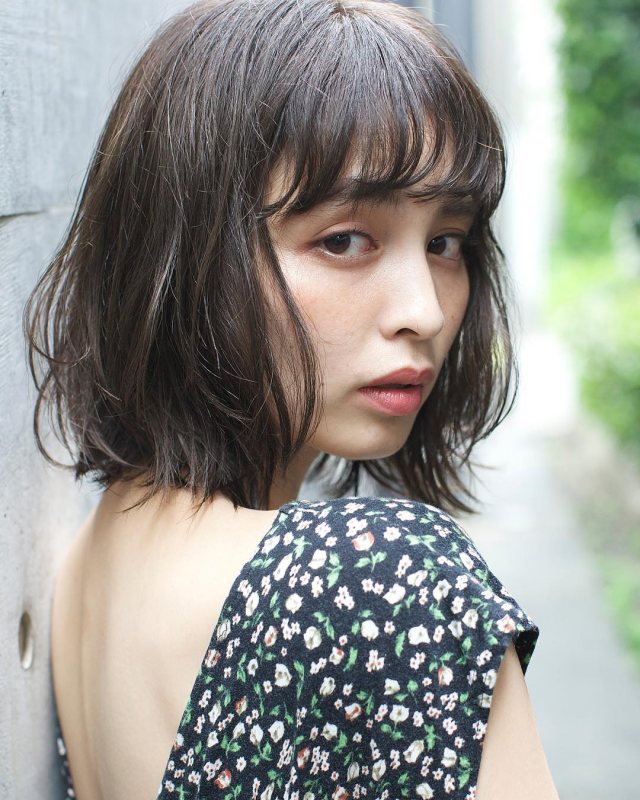 丸顔さんに似合う髪型の前髪ありのナチュラルパーマボブヘアスタイルにした女性の画像