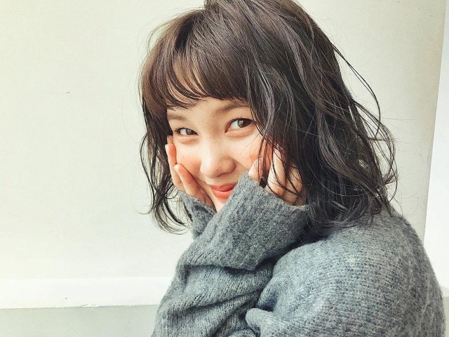 丸顔さんに似合う髪型の前髪ありのゆるふわパーマ黒髪ボブヘアスタイルにした女性の画像