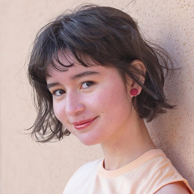 丸顔さんに似合う髪型の短め前髪ありの黒髪パーマボブヘアスタイルにした女性の画像