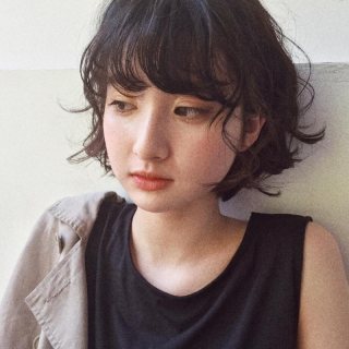 丸顔さんに似合う髪型の前髪ありの黒髪パーマショートボブヘアスタイルにした女性の画像