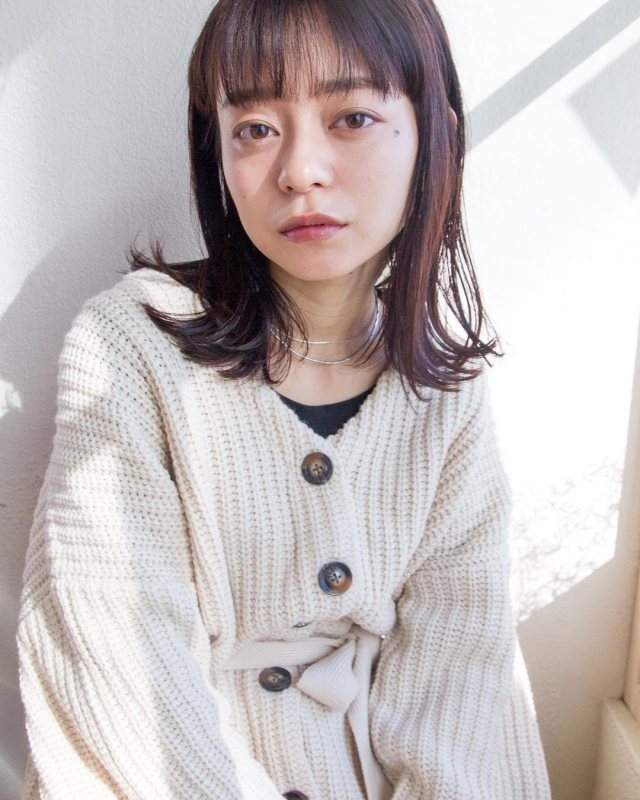 丸顔さんに似合う髪型の前髪ありの外ハネストレートミディアムボブヘアスタイルにした女性の画像