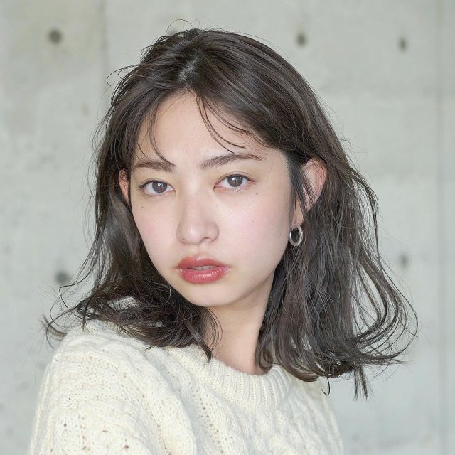 丸顔さんに似合う髪型の前髪ありのパーマ黒髪ミディアムボブヘアスタイルにした女性の画像