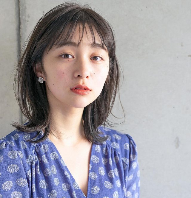 丸顔さんに似合う髪型の前髪ありの黒髪ニュアンスストレートミディアムボブヘアスタイルにした女性の画像
