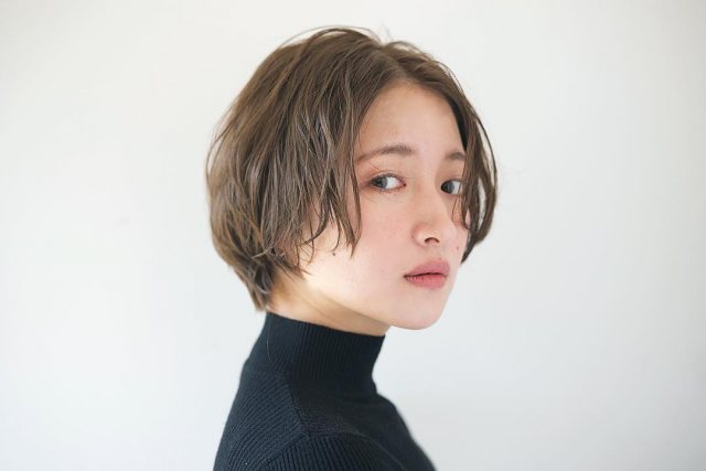 丸顔さんに似合う髪型の前髪なしセンターパートのパーマショートヘアスタイルにした女性の画像