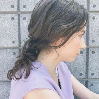 前髪なしの黒髪ロングヘアスタイルを後れ毛を出したダウンヘアアレンジにしている女性