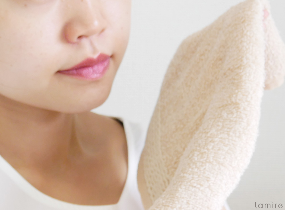 蒸しタオルを顔から外した女性の写真