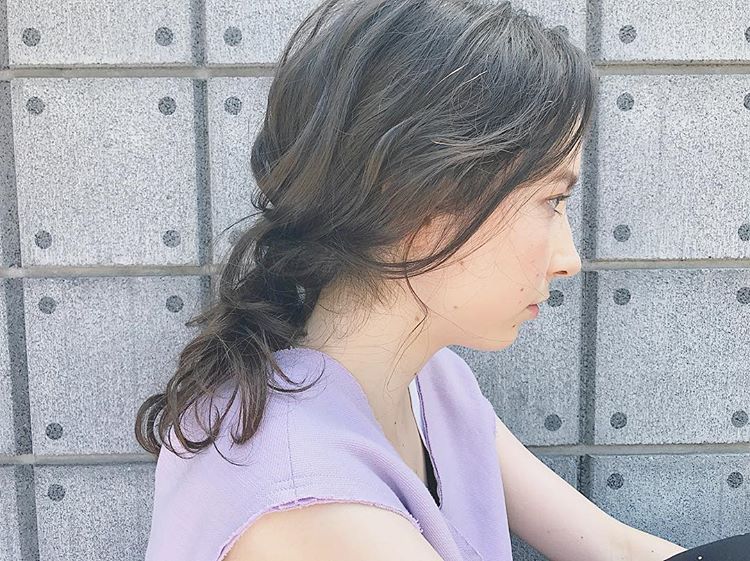 前髪なしの黒髪ロングヘアスタイルを後れ毛を出したダウンヘアアレンジにしている女性
