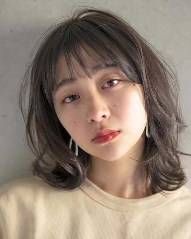 大人かわいい前髪ありのパーマウルフカットミディアムヘアスタイルにした女性の画像