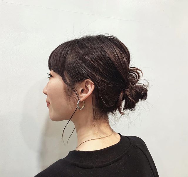 お団子にヘアアレンジしている直毛の黒髪ミディアムボブヘアスタイルの女性