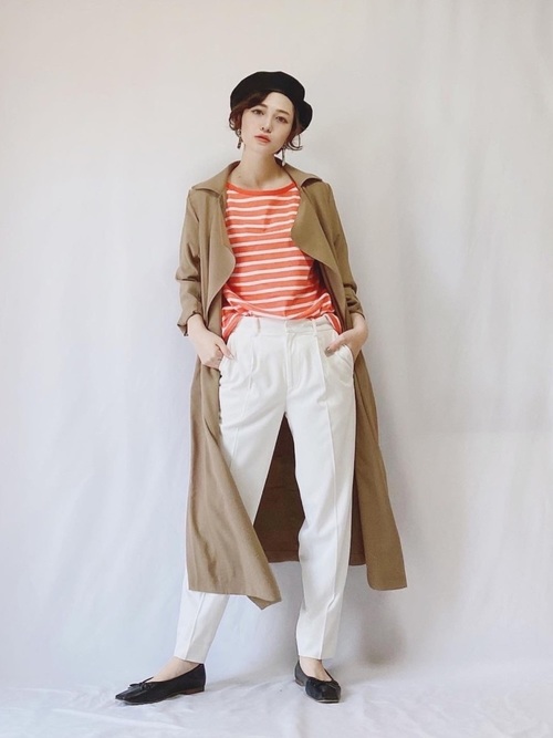 白いパンツにオレンジ色のボーダーTシャツとトレンチを着た女性