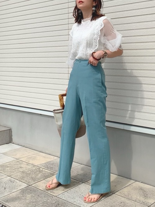 パステルブルーのワイドパンツと白レースのシャツを合わせた女性