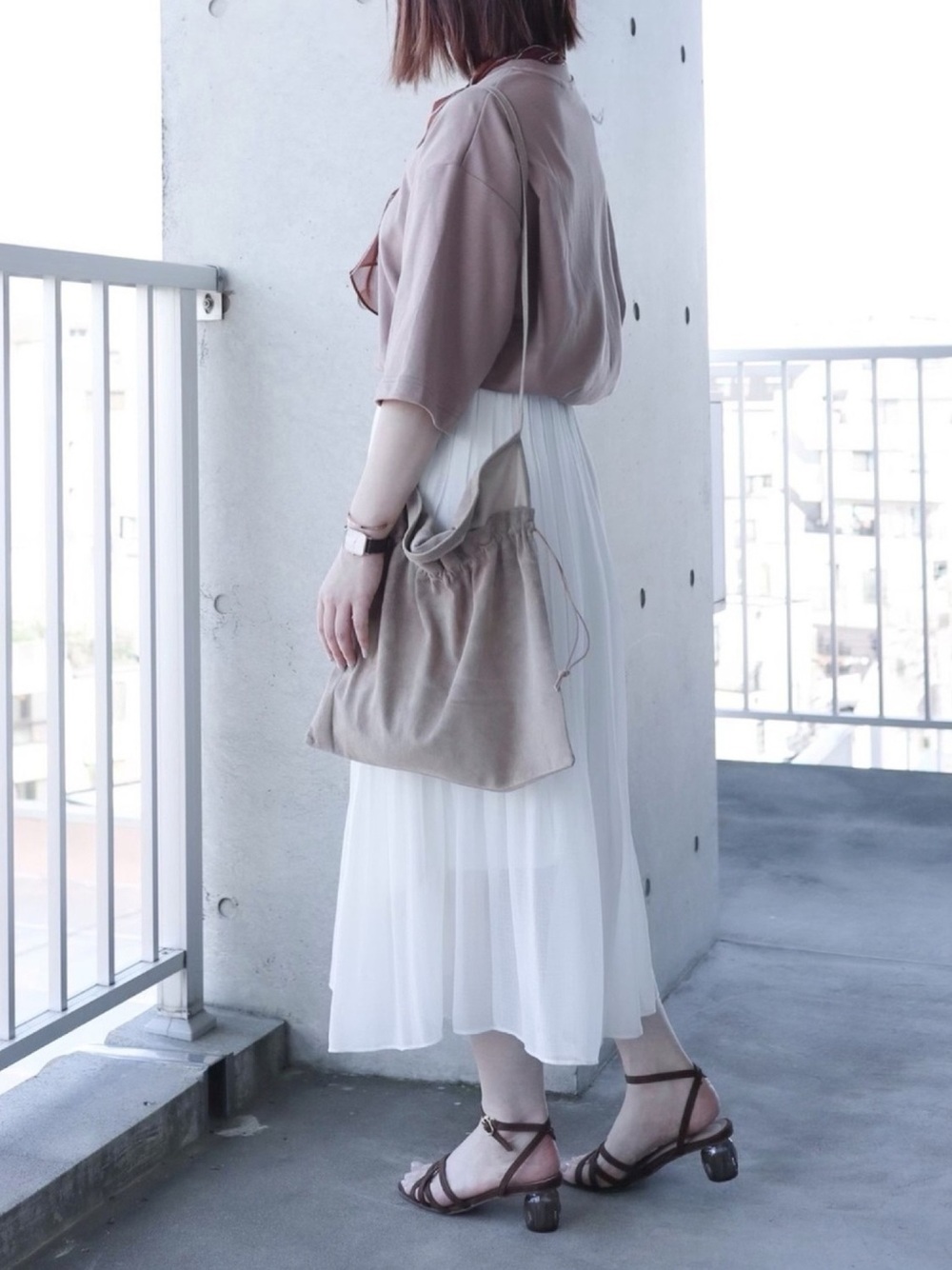 ユニクロのブラウンのTシャツとホワイトのシフォンスカートを着た女性