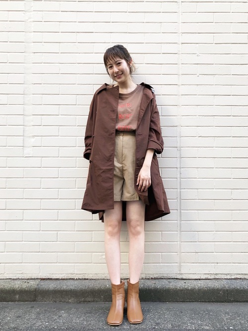ブラウントレンチコートにベージュ短パンを履いた女性