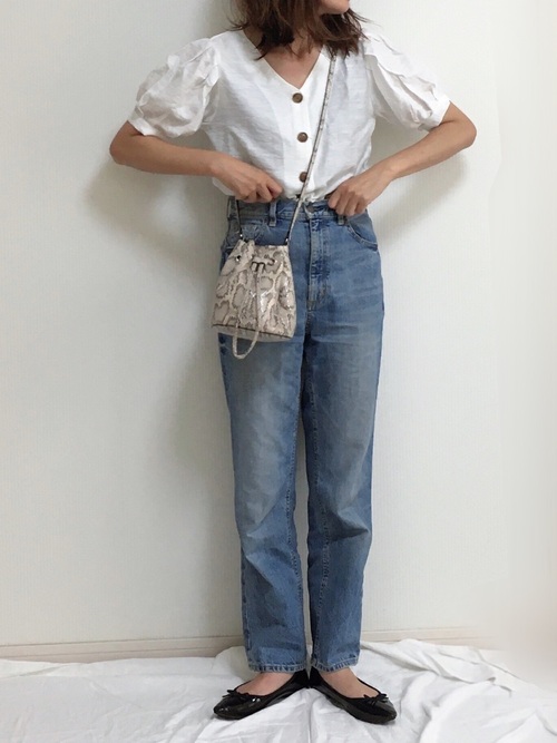 白Vネックパフスリーブブラウスとブルーストレートデニムにバレエシューズを履いた女性