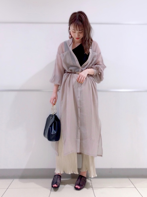 シアーロングシャツワンピースとアシメタンクトップにプリーツイージーパンツを履いた女性