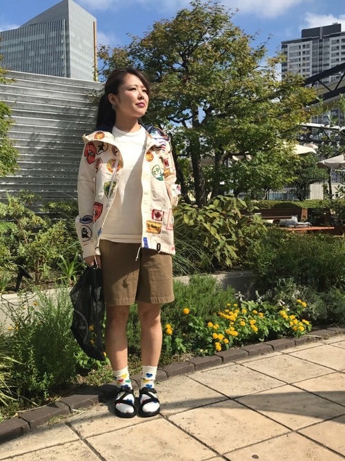 プリント柄マウンテンパーカーとグラミチのベージュショーツにスポーツサンダルを履いた女性