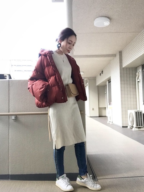スナイデルのレッドダウンコートとホワイトセーターに膝丈ホワイトスカートを履いた女性