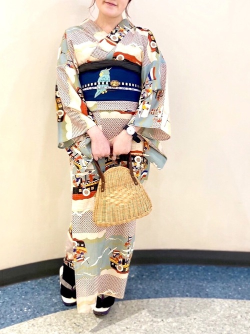 レトロマリン柄浴衣と紺色帯にベージュ三角ミニかごバッグを合わせた女性