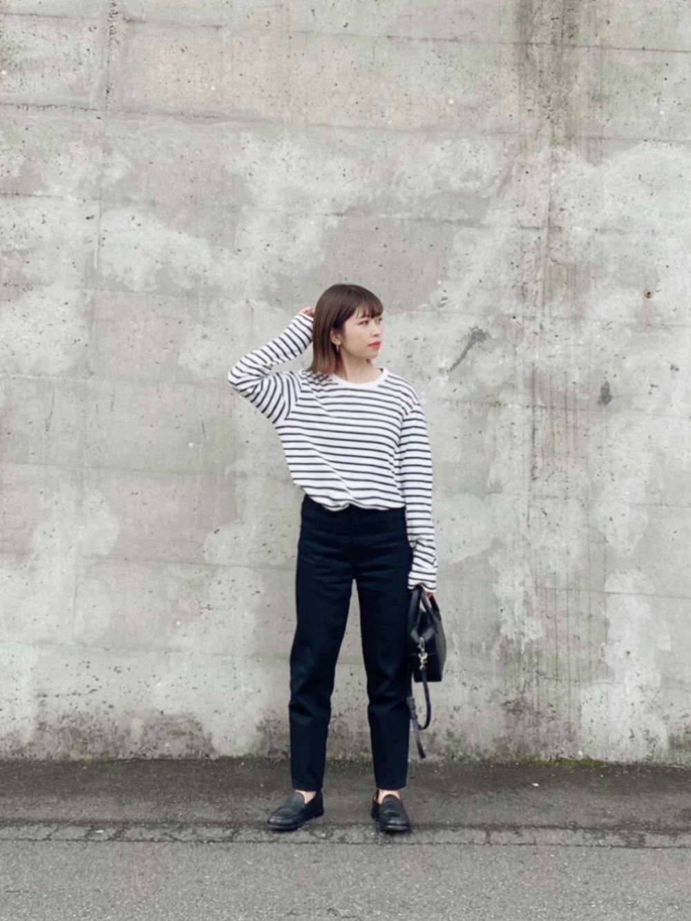 白のストライプトップスに黒パンツとローファーのコーデ