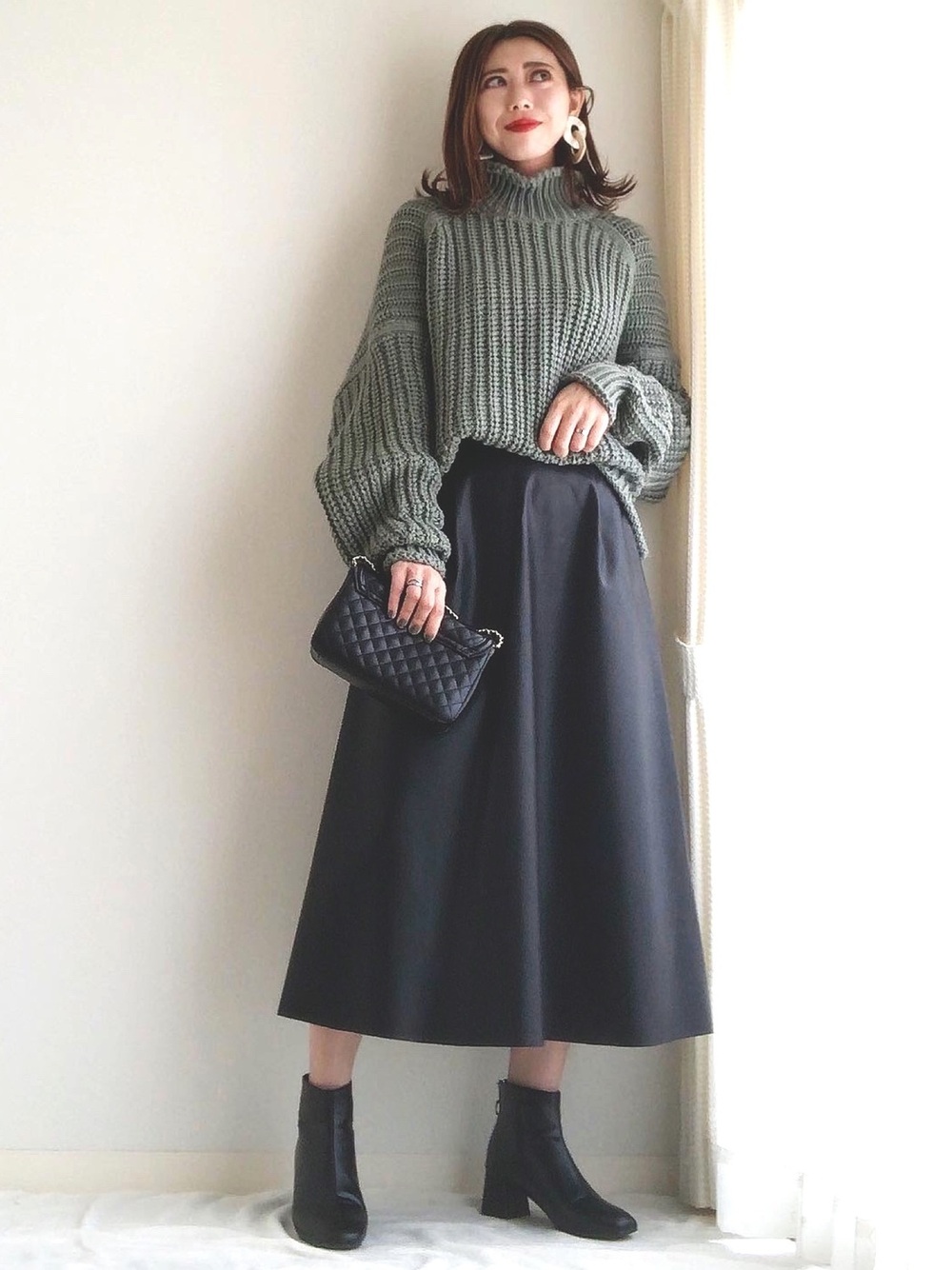 緑のニットに黒のスカートのコーデ