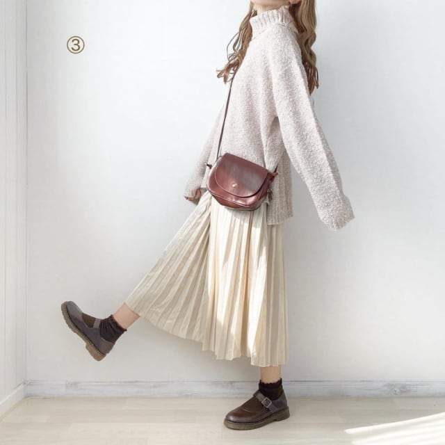 くすみピンクのブークレタートルニットにアイボリープリーツスカートを合わせ、ブラウンの靴とショルダーバッグをスタイリング