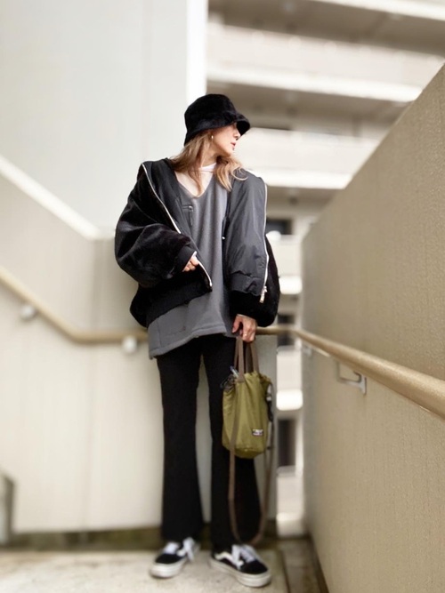 ベージュのトップスに黒のファーブルゾンを羽織り、黒のパンツとスニーカー、バケットハッとを合わせカーキ色のショルダーバッグを合わせたコーデ