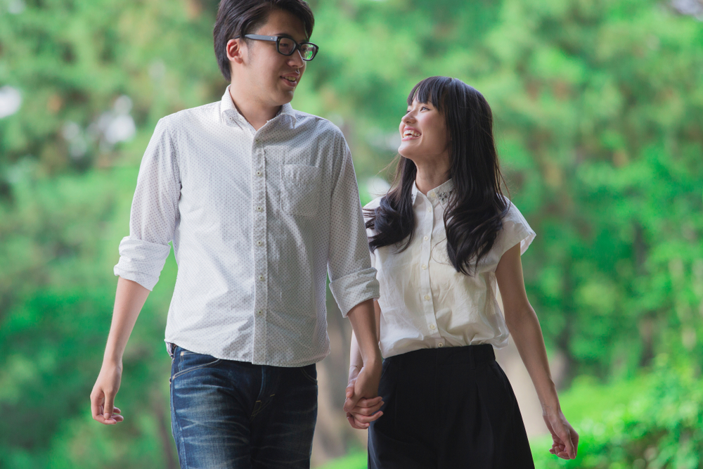 森の中を手をつないで歩く男女