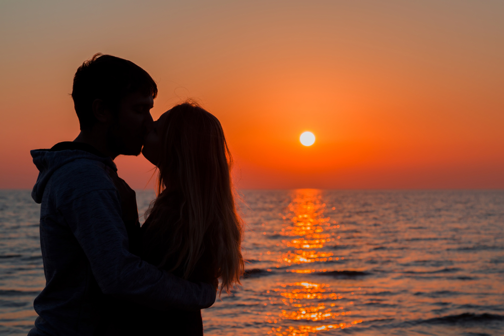 夕日に中キスする二人
