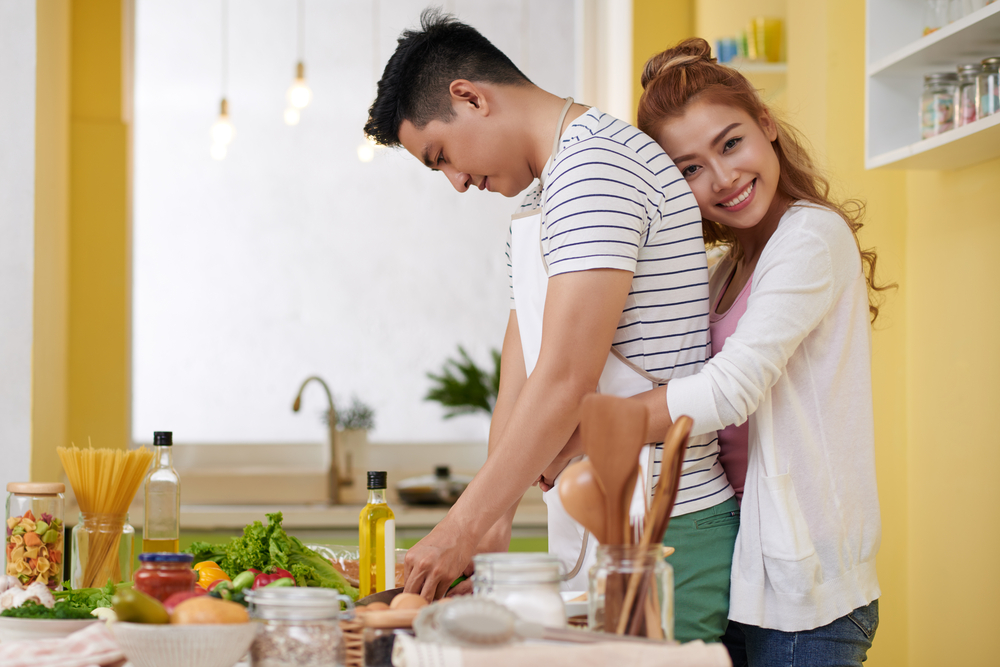 料理中の彼を後から抱き着く女性