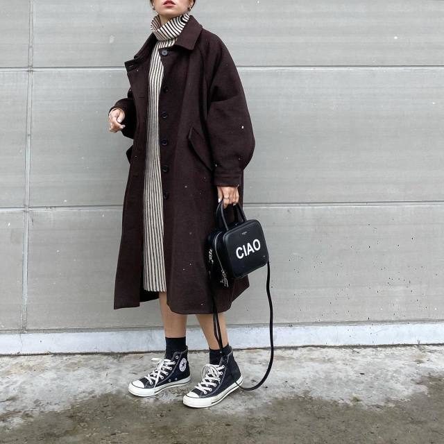 茶色のコートとタートルネックワンピースのコーデにスニーカーを合わせている女性
