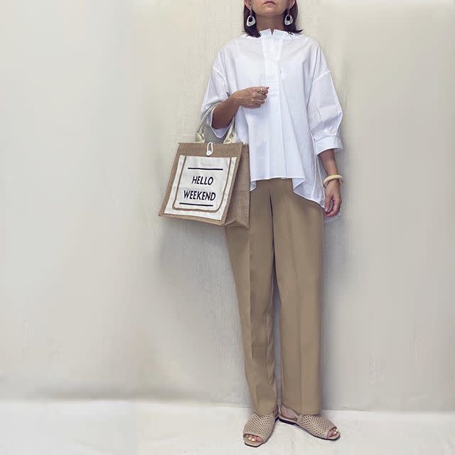 白スキッパ―ブラウスにベージュテーパードパンツを着た女性
