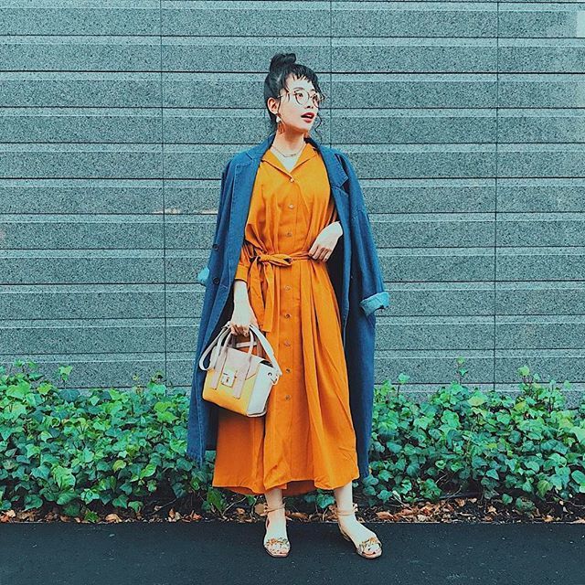 オレンジのワンピースとデニムジャケットを着た女性