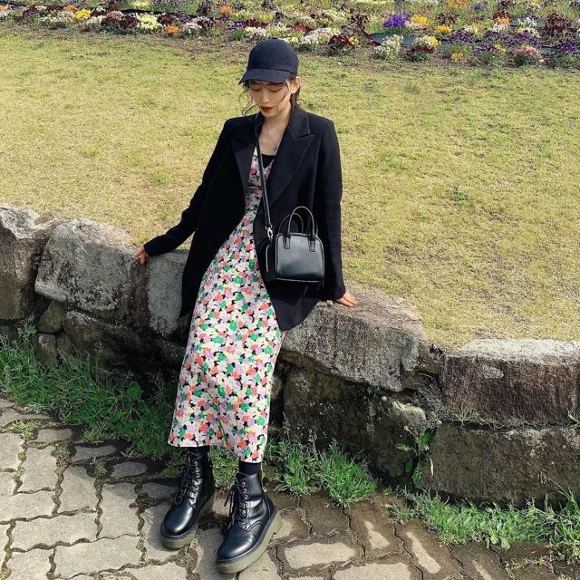 黒のテーラードジャケットに花柄ワンピを着た女性