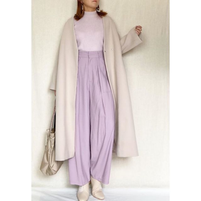 白のコートに薄紫のパンツを着用した女性