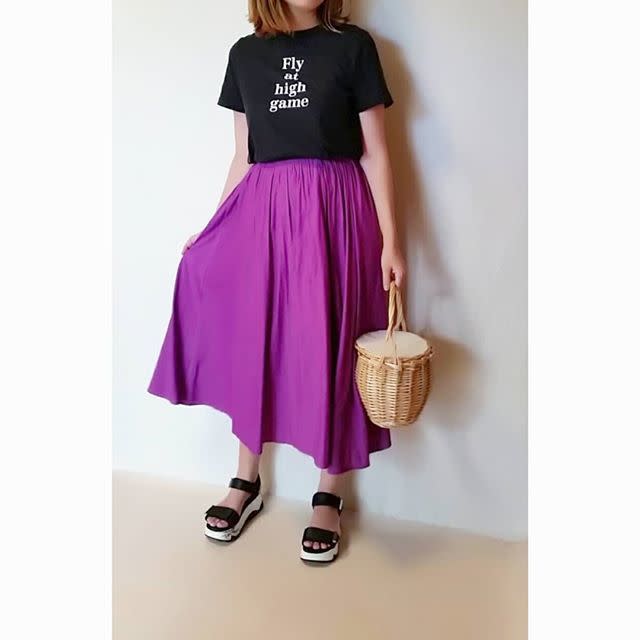 黒Tシャツに紫のスカートを合わせた女性