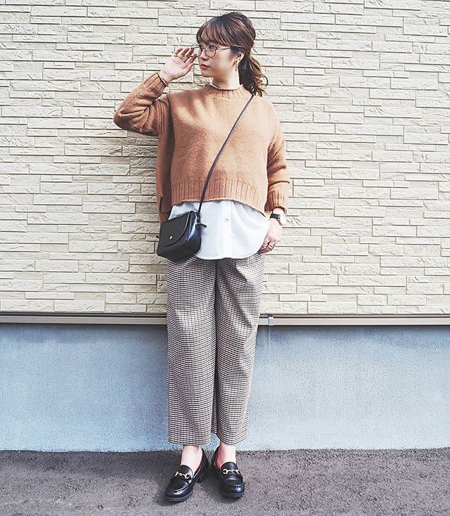 ニットとシャツとチェックパンツを着用した女性
